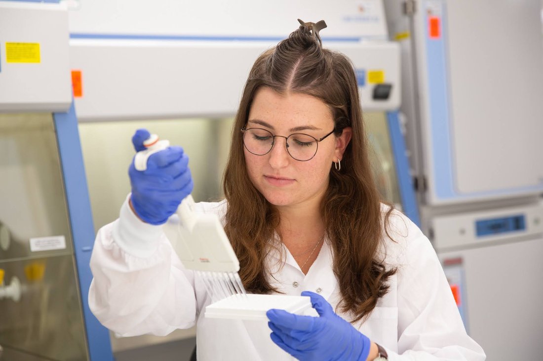 A CoreX scientist preparing samples at a biosafety cabinet
